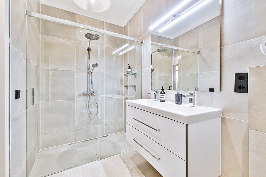 A clean bathroom with tiled walls, glass shower doors, and white vanity.