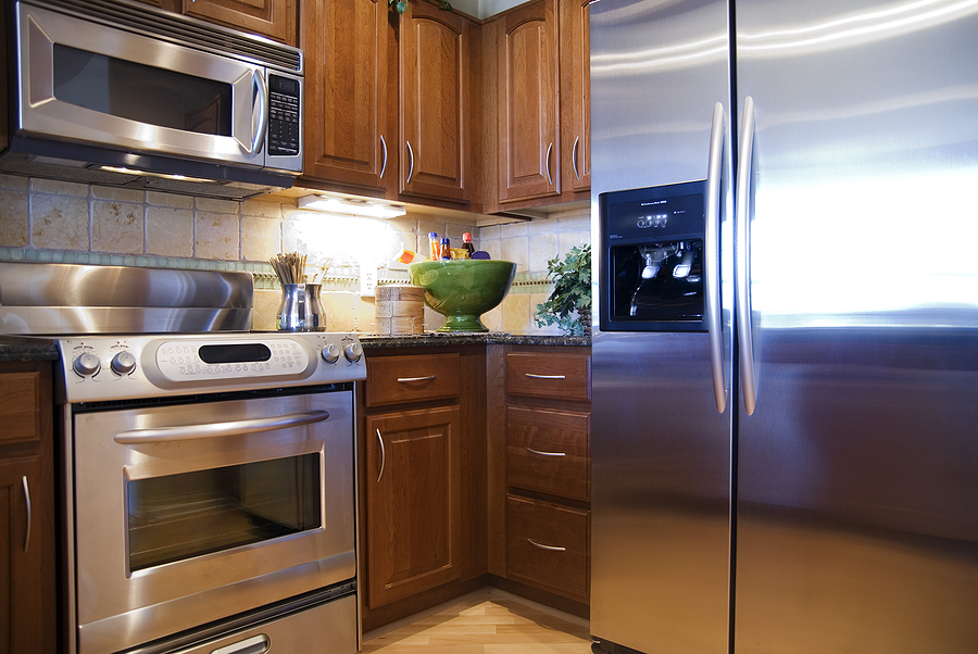 The corner of a kitchen featuring brown cabinets and stainless steel appliances, including a built-in microwave, stove, and refrigerator.