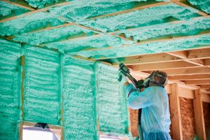Worker spraying insulation into a home